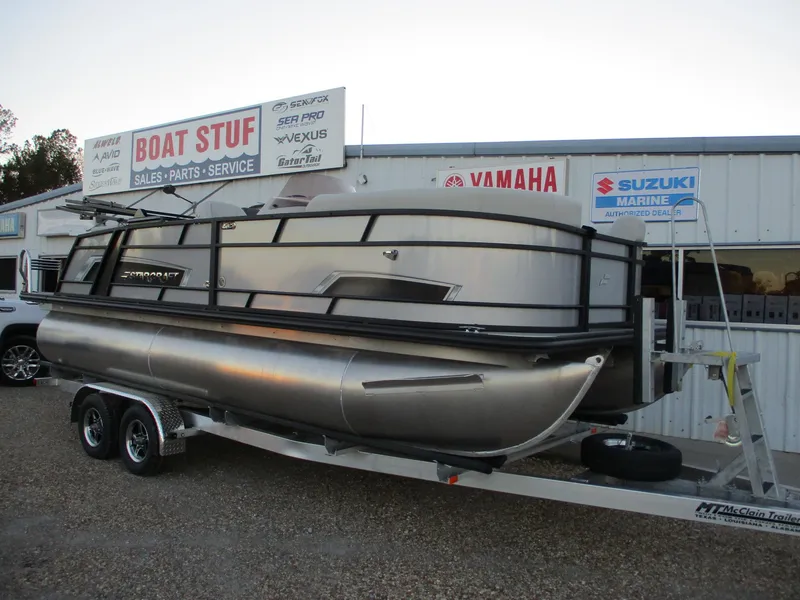 Slide: The Image of 2024 Starcraft EXS 1 Q DH pontoon boat on trailer outside dealership. - 1