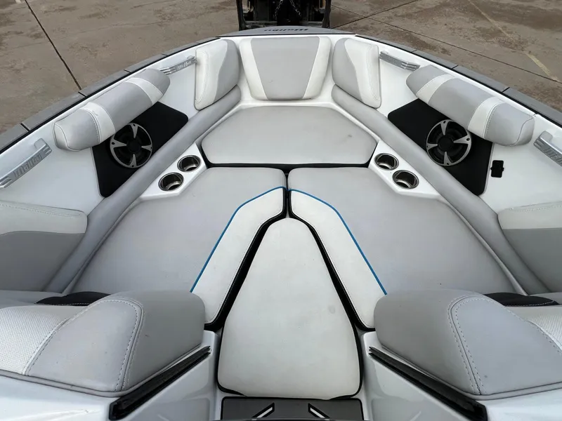 Slide: The Image of Interior of a 2018 Malibu 21 VLX boat with white cushioned seating and cup holders. - 13