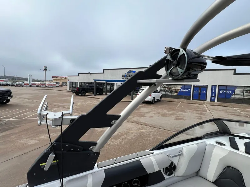 Slide: The Image of 2018 Malibu 21 VLX boat with wakeboard tower and speakers in a parking lot. - 14