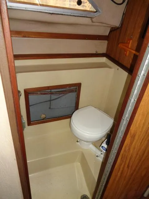 Slide: The Image of 1986 Sea Ray 250 Sundancer boat bathroom with toilet and wooden accents. - 11