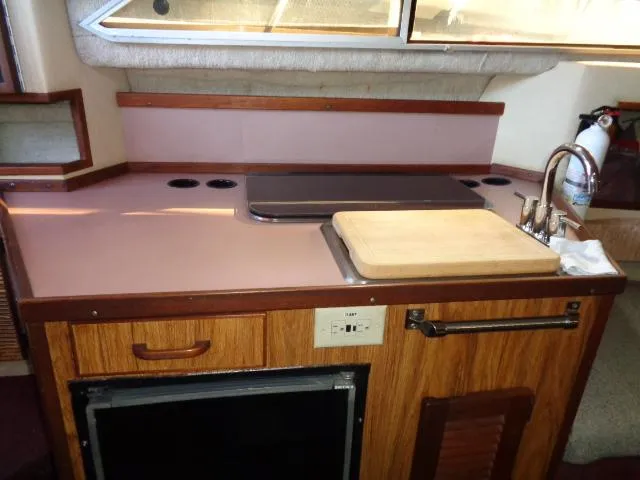 Slide: The Image of 1986 Sea Ray 250 Sundancer galley with stove, sink, and cutting board. - 3
