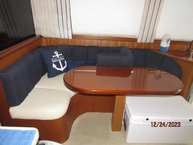 Slide: The Image of 2001 Ocean Yachts Super Sport interior dining area with cushioned seating and wooden table. - 11