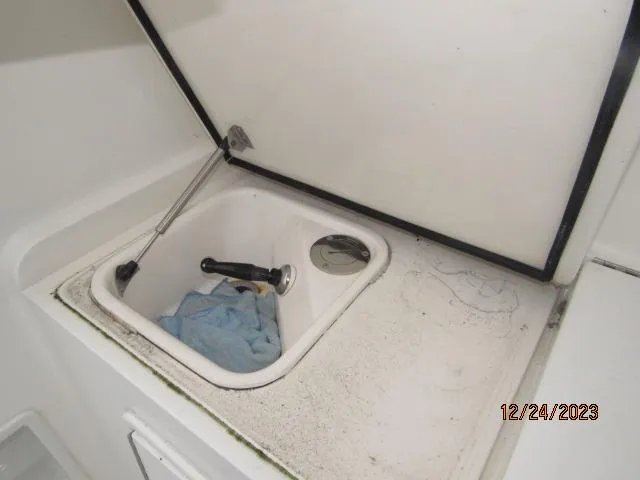 Slide: The Image of Ocean Yachts 2001 Super Sport sink area with open lid and cleaning supplies. - 15