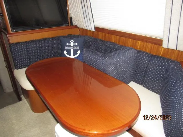 Slide: The Image of 2001 Ocean Yachts Super Sport interior dining area with wooden table and cushioned seating. - 5
