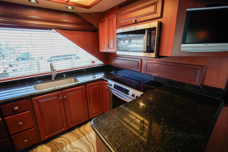 Slide: The Image of 1997 Hatteras Sportfish yacht kitchen with granite countertops, stainless steel appliances, and wood cabinetry. - 15
