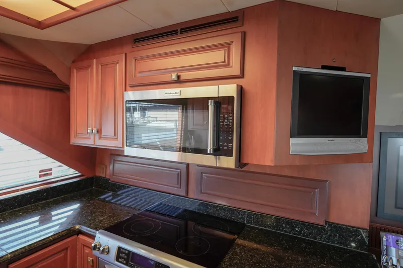 Slide: The Image of 1997 Hatteras Sportfish kitchen with microwave, TV, and black granite countertops. - 17