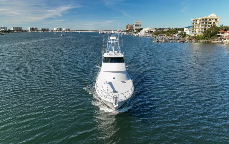 Slide: The Image of 1997 Hatteras Sportfish yacht cruising in a scenic coastal waterway. - 2