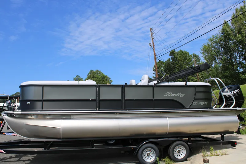 Slide: The Image of 2024 Bentley Pontoons Legacy 220 Navigator on trailer under blue sky. - 2