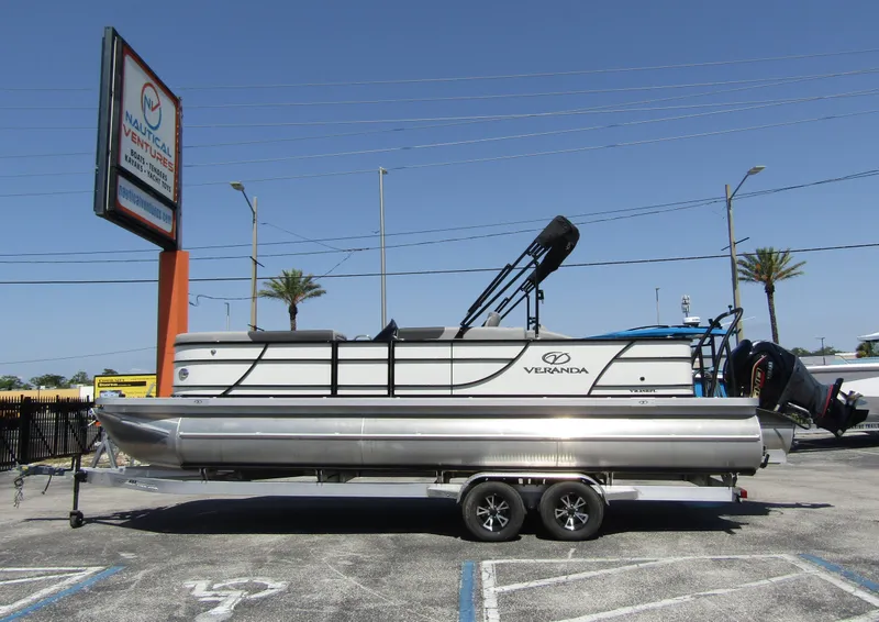 Slide: The Image of 2024 Veranda RELAX VR25RFL pontoon boat on trailer in parking lot, sunny day. - 0