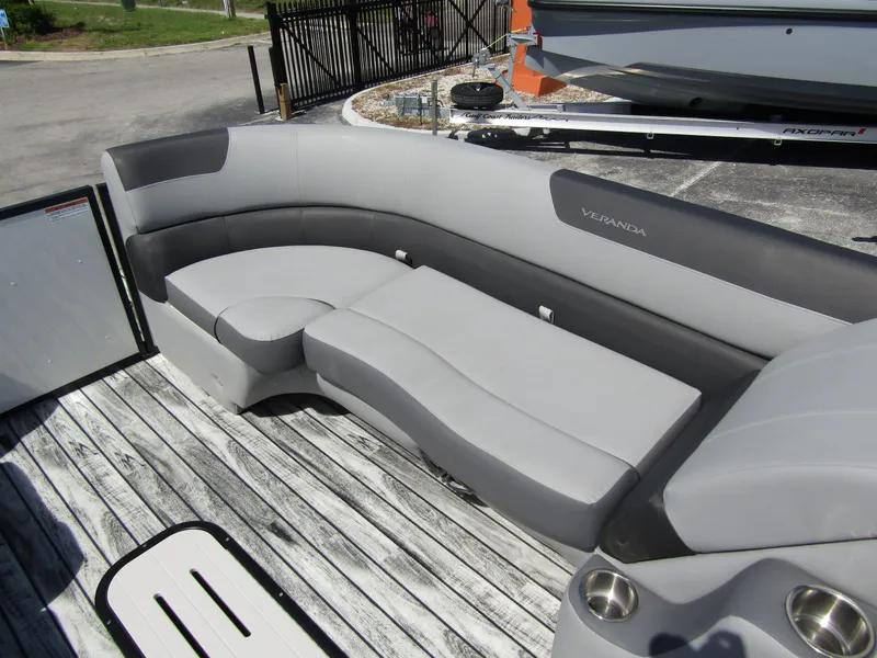 Slide: The Image of 2024 Veranda RELAX VR25RFL pontoon boat with sleek gray seating on a wooden deck. - 10