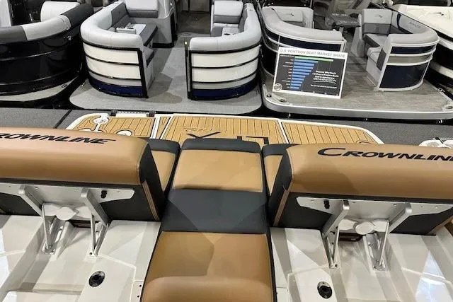 Slide: The Image of 2024 Crownline 220 SS LPX boat interior with tan and black seating, displayed at a showroom. - 18