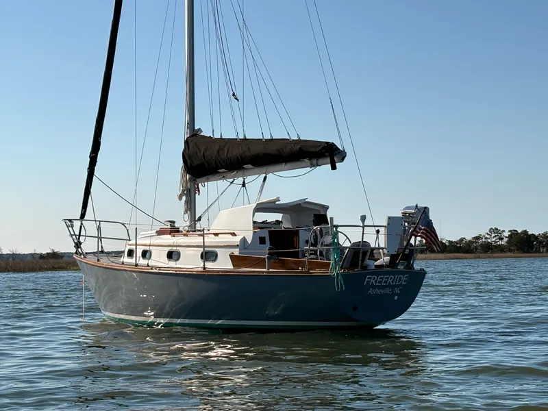 Slide: The Image of 1985 Cape Dory 270 sailboat on calm water, featuring classic design and American flag. - 0