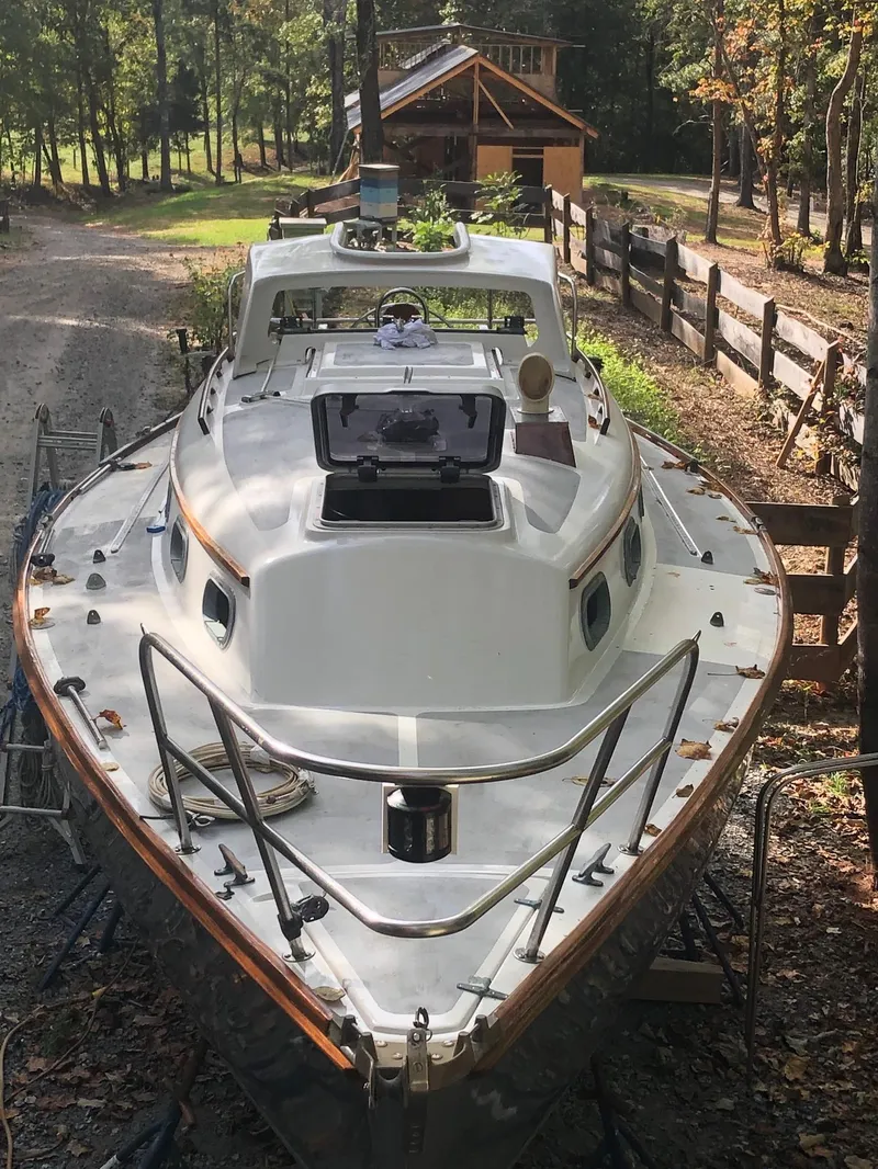 Slide: The Image of 1985 Cape Dory 270 sailboat on land near a wooden house and trees. - 15