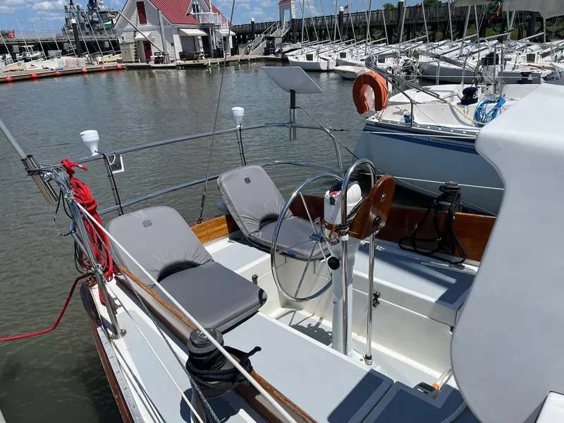 Slide: The Image of 1985 Cape Dory 270 sailboat cockpit with dual seats and steering wheel docked at marina. - 23
