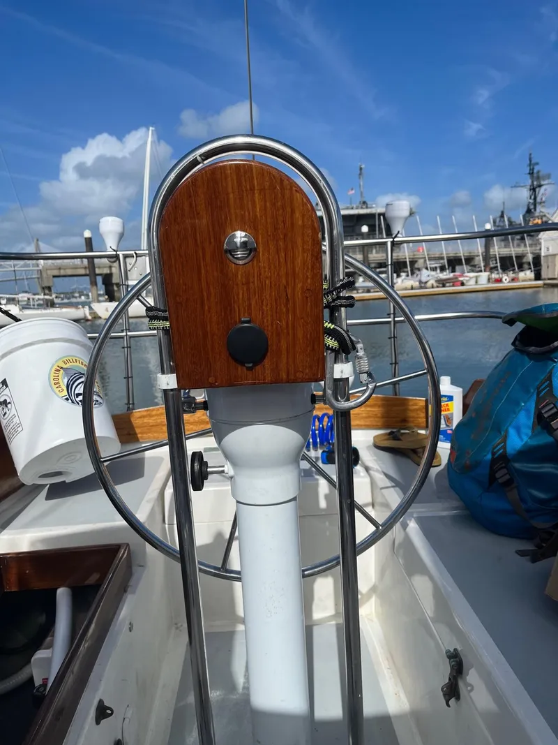 Slide: The Image of 1985 Cape Dory 270 sailboat helm with marina background. - 24
