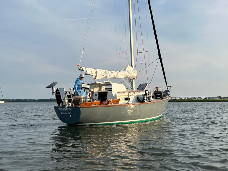 Slide: The Image of 1985 Cape Dory 270 sailboat on calm water with a person on deck. - 3
