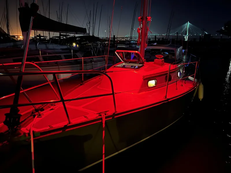 Slide: The Image of 1985 Cape Dory 270 sailboat illuminated by red lights at night in a marina. - 33