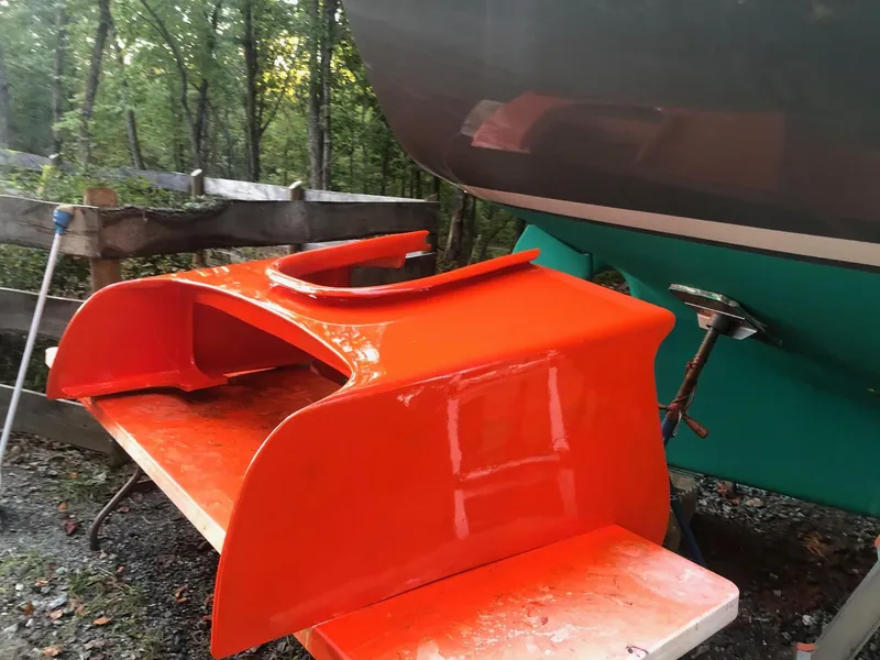 Slide: The Image of Bright orange part of a 1985 Cape Dory 270 boat being painted outdoors. - 35