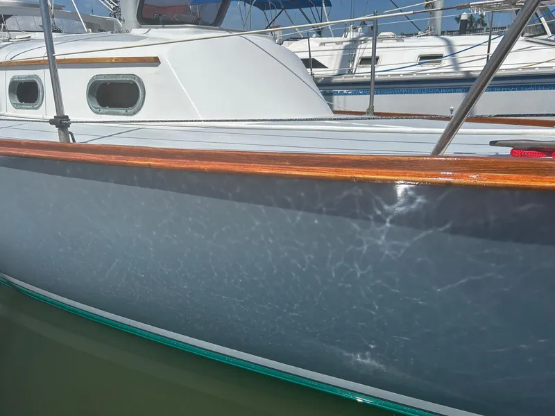 Slide: The Image of 1985 Cape Dory 270 sailboat with polished hull and wooden trim in marina. - 7