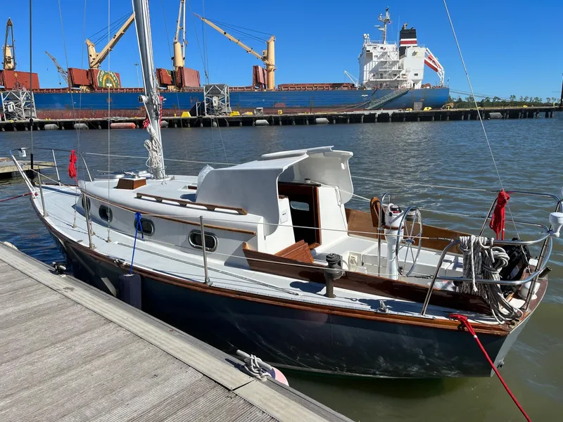 Slide: The Image of 1985 Cape Dory 270 sailboat docked at a marina with cargo ships in the background. - 9