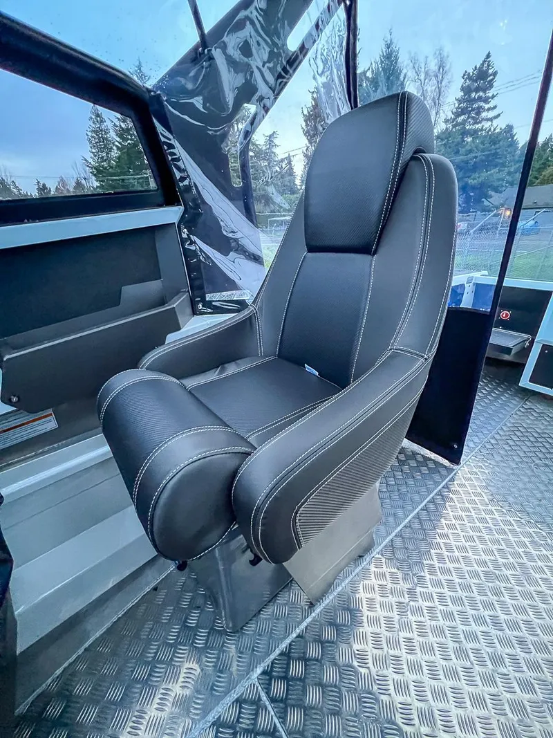 Slide: The Image of Captain's chair inside 2024 Stabicraft 1850 Fisher boat, featuring black upholstery and white stitching. - 8