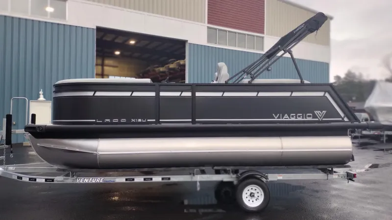Slide: The Image of 2024 Viaggio Lago X18U pontoon boat on trailer outside warehouse. - 3