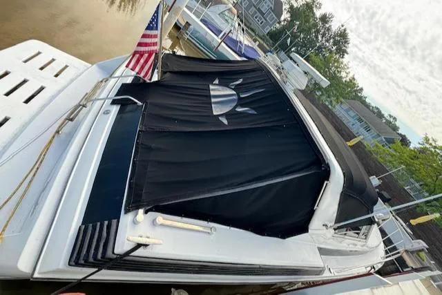 Slide: The Image of 1988 Chris-Craft Amerosport boat docked with black sun cover and American flag. - 46