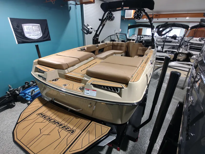 Slide: The Image of 2024 Moomba Makai boat interior in showroom, featuring tan seating and teak-style flooring. - 15