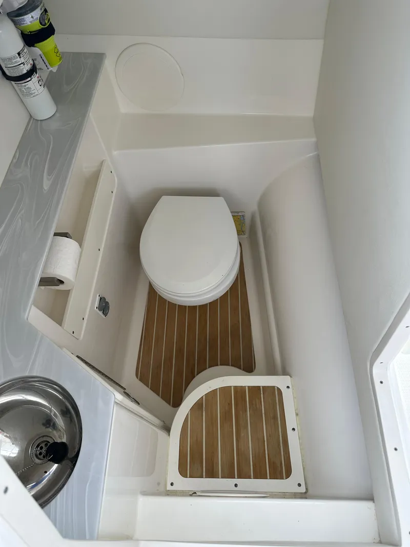 Slide: The Image of 2021 World Cat 280 DC-X boat bathroom with toilet, sink, and wooden flooring. - 17