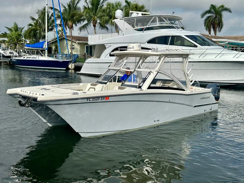 Slide: The Image of 2021 World Cat 280 DC-X boat docked in marina with palm trees and yachts. - 2