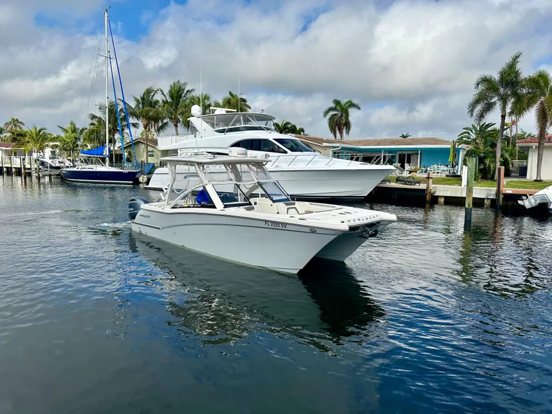Slide: The Image of 2021 World Cat 280 DC-X boat cruising in a marina with palm trees and yachts. - 3