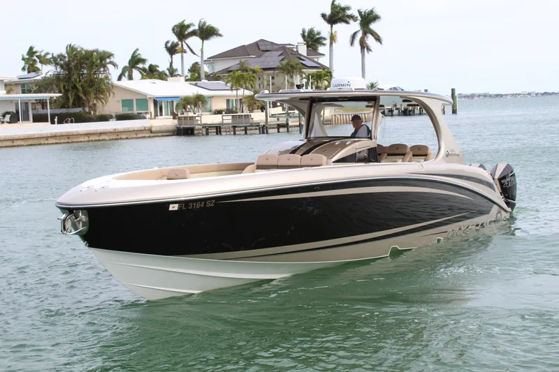 Slide: The Image of 2021 Mystic Powerboats M4200 cruising in a coastal area with palm trees and houses. - 13