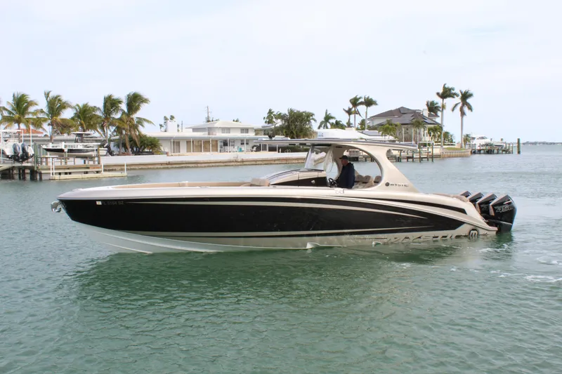 Slide: The Image of 2021 Mystic Powerboats M4200 cruising in a tropical waterfront setting. - 14