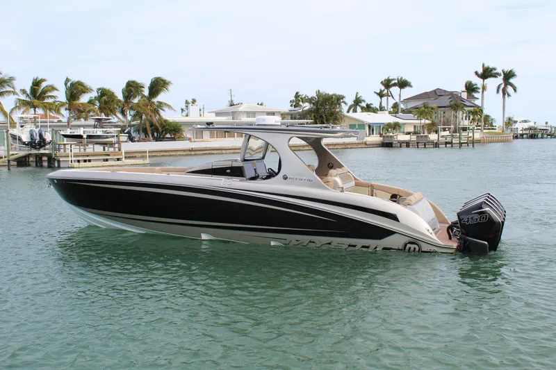 Slide: The Image of 2021 Mystic Powerboats M4200 on calm waters near a coastal dock. - 15