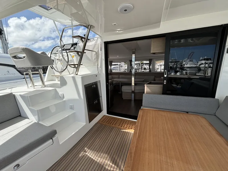 Slide: The Image of 2025 Lagoon 42 yacht interior with seating, steering wheel, and wooden table. - 21