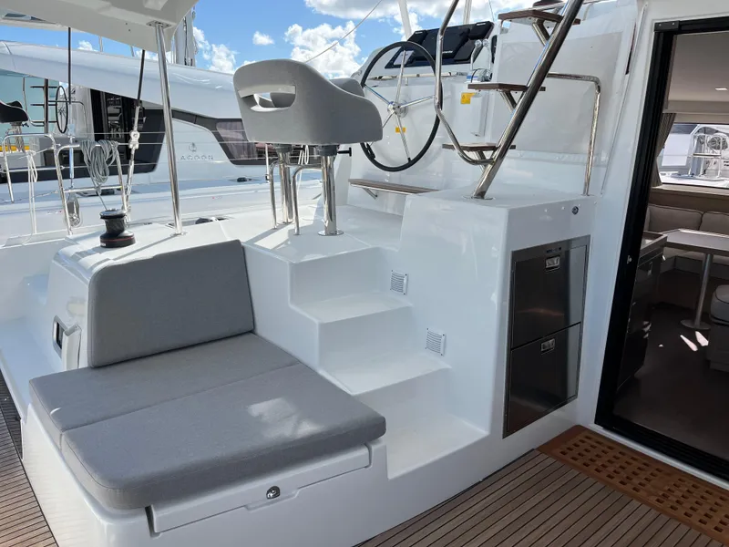 Slide: The Image of 2025 Lagoon 42 yacht cockpit with seating, helm, and stairs under a blue sky. - 38