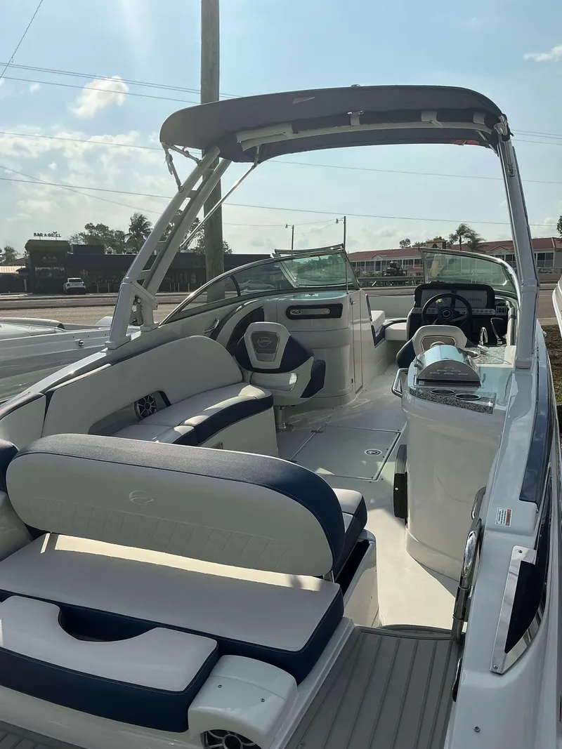 Slide: The Image of 2024 Crownline 290 XS boat interior with seating and helm, under sunny skies. - 5