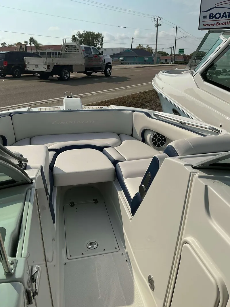 Slide: The Image of 2024 Crownline 290 XS boat interior with white and blue seating, parked outdoors. - 7