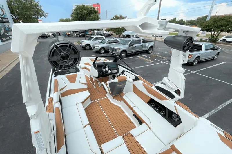 Slide: The Image of 2023 Nautique S21 Super Air boat interior with white and tan seating, large speakers, and modern dashboard. - 19