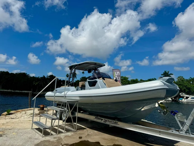 Slide: The Image of 2025 Ranieri CAYMAN 28 EXECUTIVE boat on trailer by the water under a blue sky. - 3