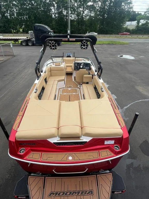Slide: The Image of 2024 Moomba Tykon boat with red exterior and beige interior, parked on pavement. - 12
