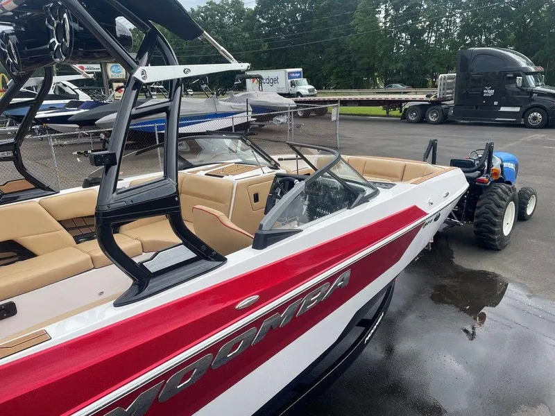 Slide: The Image of 2024 Moomba Tykon boat with red and white exterior, parked outdoors. - 30