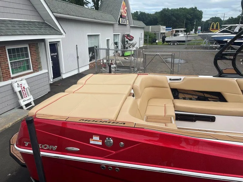 Slide: The Image of 2024 Moomba Tykon boat with red exterior and beige interior, parked near a building. - 5