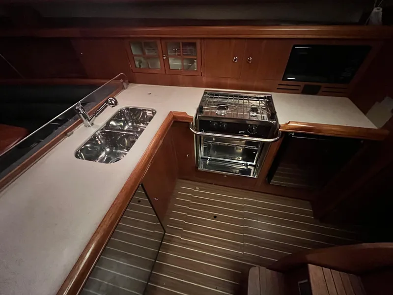Slide: The Image of Hunter 38 2005 yacht kitchen with double sink, stove, and wooden cabinetry. - 23