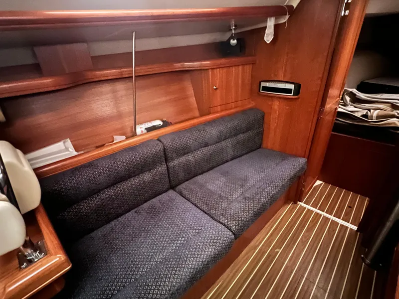 Slide: The Image of Interior of 2005 Hunter 38 sailboat with blue cushioned seating and wooden cabinetry. - 26