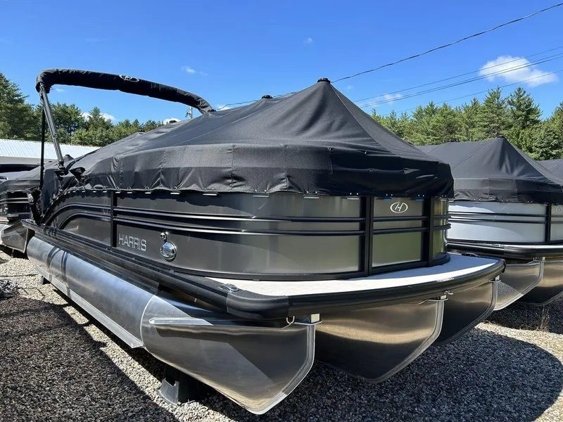 Slide: The Image of 2024 Harris Sunliner 210 pontoon boat with black cover, parked outdoors. - 3