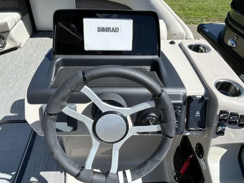 Slide: The Image of 2024 Harris Sunliner 210 boat dashboard with steering wheel and Simrad display. - 11