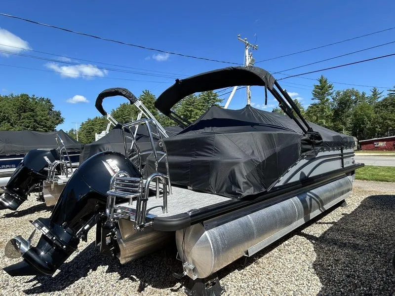 Slide: The Image of 2024 Harris Sunliner 210 pontoon boat with black cover, parked outdoors on gravel. - 3