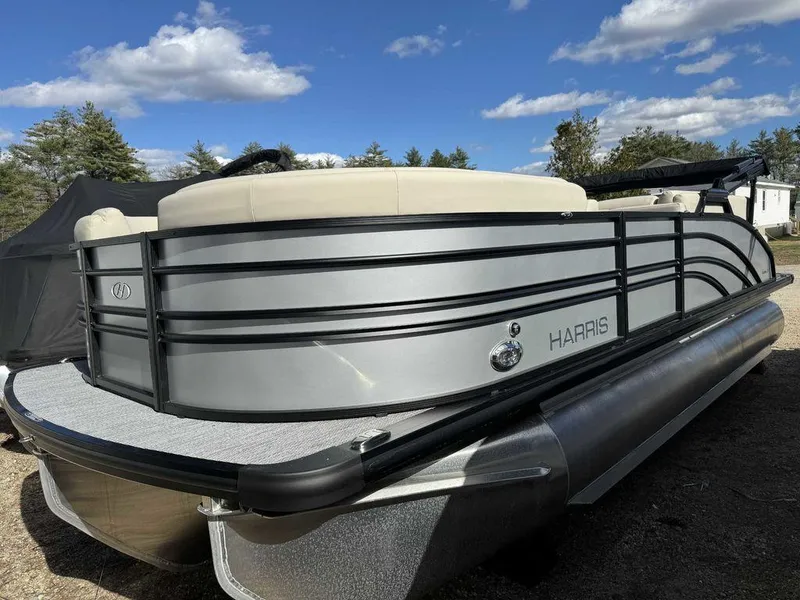 Slide: The Image of 2024 Harris Sunliner 210 pontoon boat with sleek silver design under a blue sky. - 5