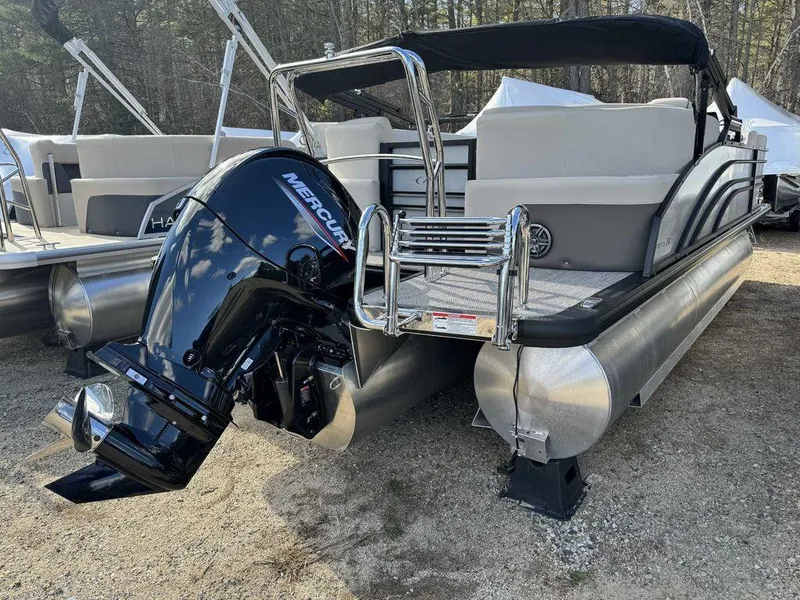 Slide: The Image of 2024 Harris Sunliner 210 pontoon boat with Mercury outboard motor, docked on gravel. - 8